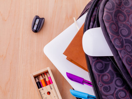 Backpack with school supplies laptop,book stationary,mouse,pen,ruler, and color pencil on wooden table .の写真素材