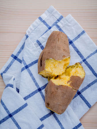 Cooked whole sweet potatoes with napkin on wooden table.の写真素材
