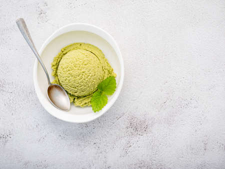 Matcha green tea ice cream with matcha whisk brush setup on white stone background . Summer and...