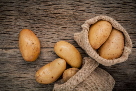 Fresh organic potatoes in hemp sake bags on rustic wooden background. Row organic potatoes on old wooden background with copy space .の写真素材