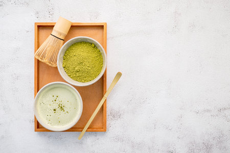 Matcha green tea powder with bamboo matcha whisk brush setup on white concrete background .の写真素材