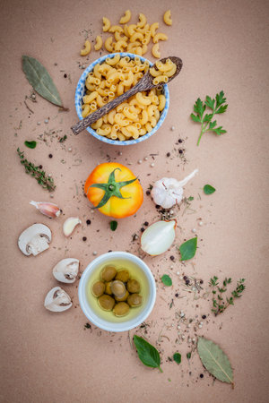 Italian food concept pasta with vegetables olive oil flavored with spices herb rosemary ,thyme,parsley and champignon mushroom set up with brown background.の写真素材