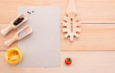 Food background for tasty Italian dishes with blank brown paper and vintage pasta ladle on wooden background. Top view italian foods concept and menu design with copy space.の写真素材