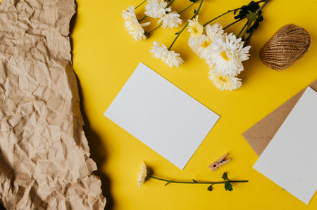 blank card with envelope and flower is placed on yellow background
