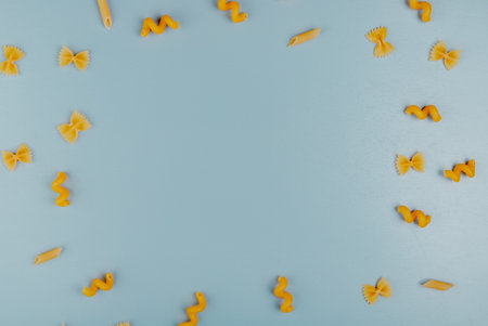 top view of macaronis as farfalle fusilli penne set in round shape on blue background with copy spaceの写真素材