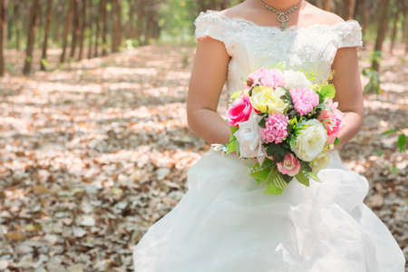 Bride holding big wedding bouquet in the forest.