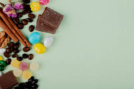 top view of nuts in chocolate marmalade candies coffee beans and cinnamon sticks on the table with copy spaceの写真素材