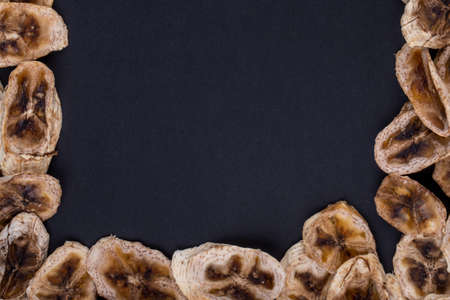 top view of dried banana chips isolated on black background with copy spaceの写真素材