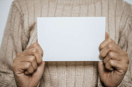 Hand held an open card or letter and placed on the chest, the blank cover mock-up.の写真素材
