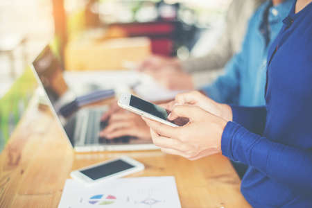 business woman hand working on smart phone and laptop computer and business graph information...