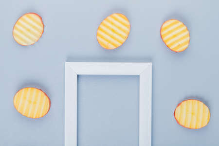 top view of potato slices around frame on blue background with copy spaceの写真素材
