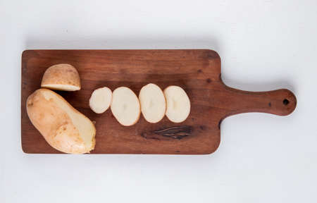 top view of cut and sliced potatoes on cutting board on white background