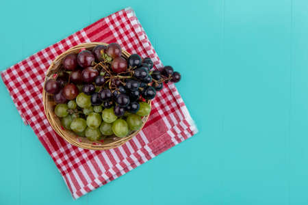 top view of grapes in basket on plaid cloth on blue background with copy spaceの写真素材