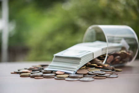 group of coins and euro banknotes in a glass jar.