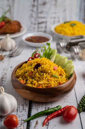 Turmeric rice in a Brown cup with spices on a white wooden floor