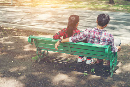 Young teenagers couple in love sitting together on the bench in the park .の写真素材