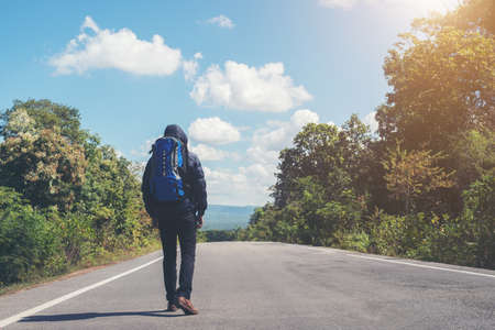 Rear of hiker man walking on the rural road on vacation. Holiday tourism concept.の写真素材