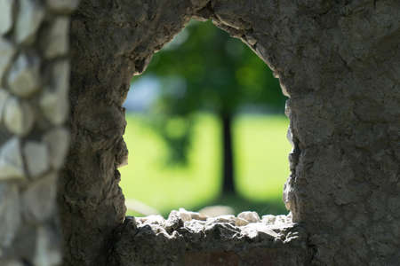 stone background with window and view of blurred green tree.の写真素材