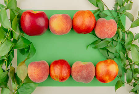 top view of peaches on green and white background decorated with leavesの写真素材