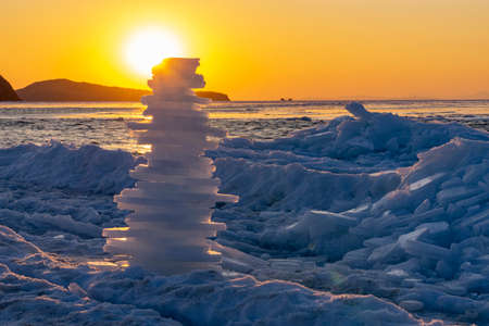 Ice pyramid on the background of a beautiful sunset over the frozen seaの写真素材
