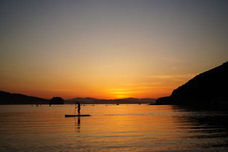 Beautiful sunset with silhouettes of people on SUP-surfer. Vladivostok, Russia
