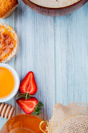 top view of half cut strawberries with oats crispbread peach syrup cupcake butter on wooden background with copy spaceの写真素材