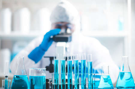 Doctor or scientist researcher working in laboratory holding a syringe with liquid virus vaccines,...