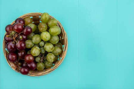 top view of grapes in basket on blue background with copy spaceの写真素材