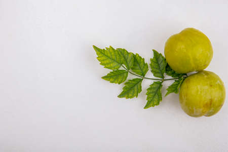 top view of green pluots with leaves on white background with copy spaceの写真素材