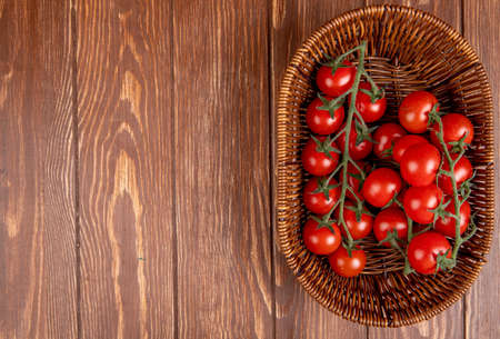 top view of tomatoes in basket on right side and wooden background with copy spaceの写真素材