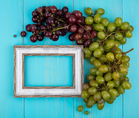 top view of grapes and frame on blue background with copy spaceの写真素材