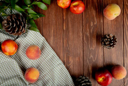 top view of peaches and pinecones on cloth on wooden backgroundの写真素材