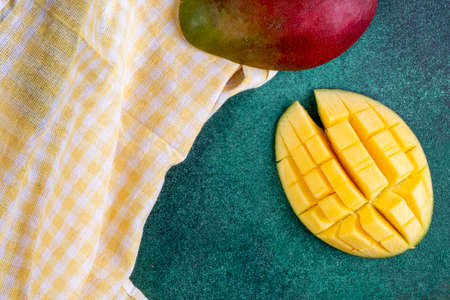 top view sliced mango with a yellow kitchen towel on a green backgroundの写真素材