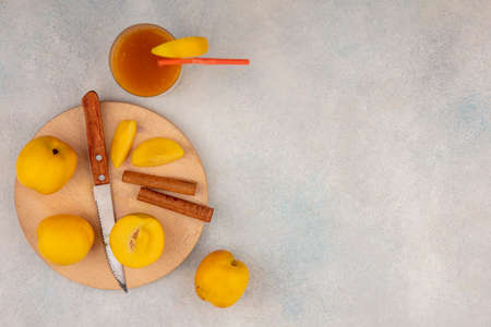 top view of delicious yellow peaches on a wooden kitchen board with knife with cinnamon sticks on a...