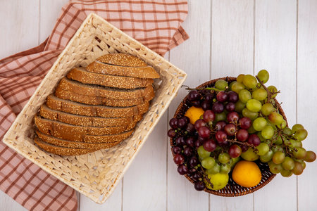 top view of sliced brown seeded cob in basket on plaid cloth and basket of fruits as grape nectacot...