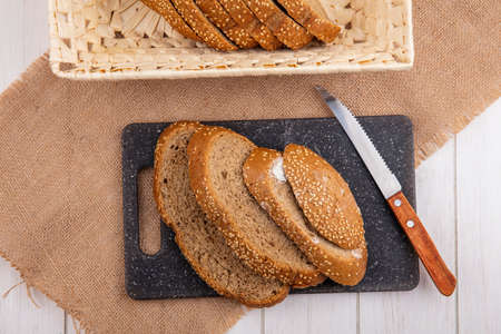 top view of sliced brown seeded cobs in basket and on cutting board with knife on sackcloth on...