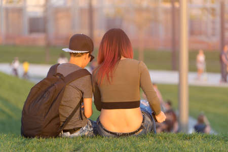 Krasnodar, Krasnodar region-June 8, 2017: young man and girl sitting back on green grass in Galitsky Park.の写真素材