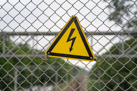 yellow triangle with black lightning on a metal mesh background
