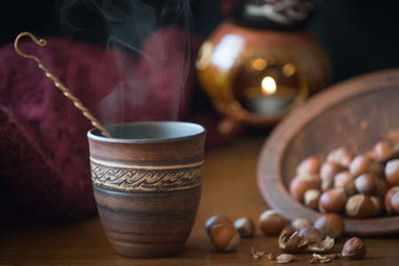 Dark background with a hot drink in a ceramic Cup and the scattered nuts hazelnuts on a wooden surface.の写真素材