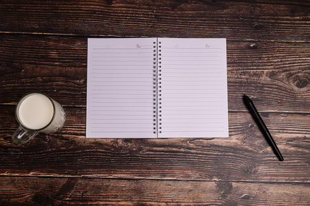 The notebook and a glass of milk are on the desk.の素材