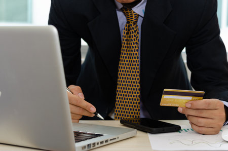 Business man holding a credit card shopping online marketing or digital transactions over the Internet with a laptop computer and a smartphone.の素材