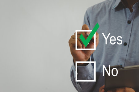 businessman holding a pen with a green check mark on the square on a virtual screenの素材