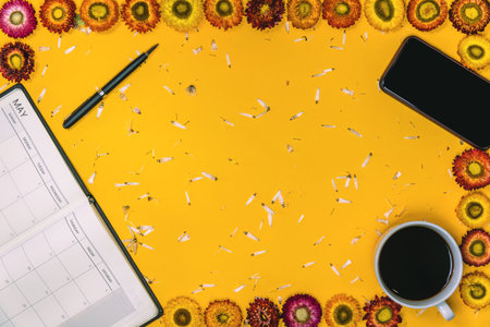 Top view concept of pastel yellow background. Colorful flowers that are arranged shape with a notebook pen and Cup of coffee placed.の素材