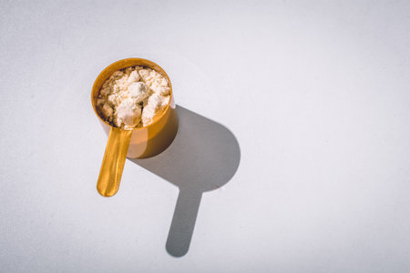 Scoops filled with protein vanilla powders on white background. top view with copy space for text. Sun lightの素材