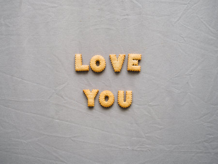 Bicuits arrange into word on grey background. Concept of word LOVE YOU.の素材
