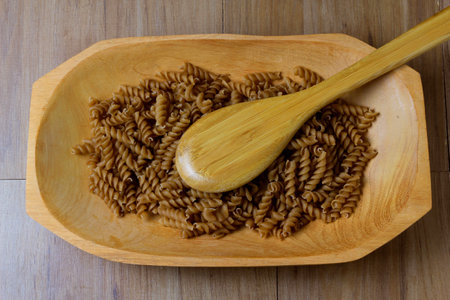 portion of raw whole noodles, wooden bowl, twisted, wooden table, top viewの素材