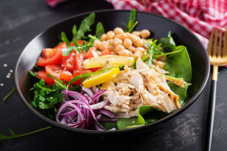Buddha bowl dish with chicken fillet, chickpeas, tomatoes, red onion, fresh green salad and seed sesame. Healthy balanced eating.の素材