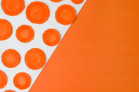 Fresh carrot slices isolated on paper backgroundの素材
