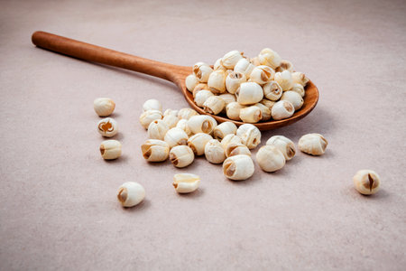 Composition of raw lotus seeds .The asian popular seed for food ,desserts and herbal medicine in wooden spoon on brown background.の素材