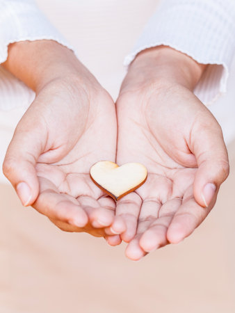 Girl holding wood shape of heart . Concept for giving love.の素材